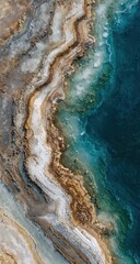 Aerial view of sculpted earth meeting a vibrant body of water