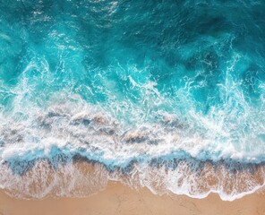 High-angle view of turquoise waves crashing on light beige sand