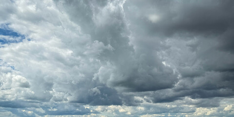 Fototapeta premium Stormy sky with dark, snowy clouds on a spring day. Clouds are floating across the sky. Dark blue clouds swiftly floating across blue sky. Storm dramatic clouds are floating across the sky. Hurricane.