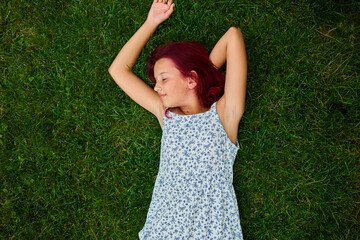 Teen girl relaxes on green grass in a peaceful outdoor setting during a sunny day