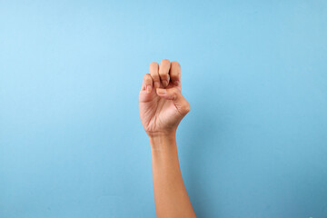 Hand Making The Letter E In American Sign Language Against Blue Background
