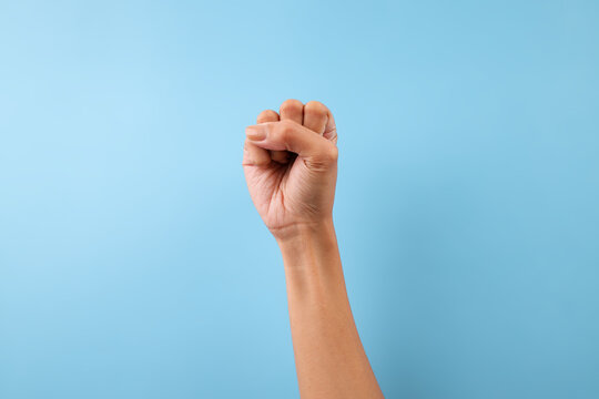 Hand Making The Letter S In American Sign Language Against Blue Background