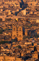 Aerial view of Notre Dame Cathedral over Parisian cityscape during golden hour of sunset in Paris, France.