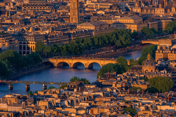 Aerial view of the Pont Neuf and Paris cityscape at sunset over the Seine River illuminated by golden hour.