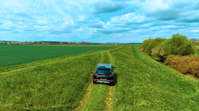 Car navigating rural landscape along bumpy dirt paths between crop fields for agricultural inspection. Car driving slowly through grassy trails in rural area, inspecting crop growth while maneuvering