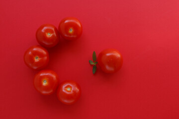 Fresh red tomatoes with fresh green basil leaves on red background