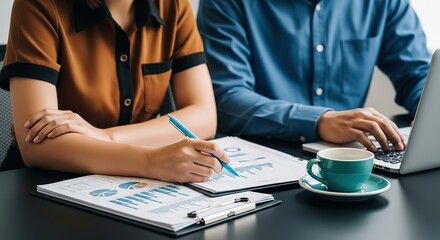 Two professionals collaborate on financial reports with a laptop and coffee highlighting teamwork and data analysis