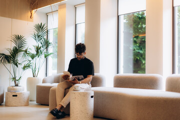 Businessman reading magazine in modern office lobby waiting area