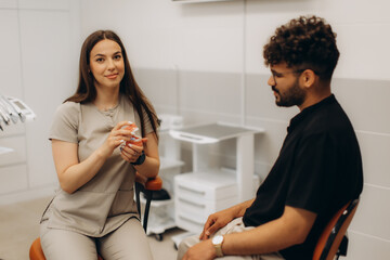 Dentist showing teeth model to patient in dental clinic