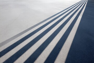 Fototapeta premium Long, dramatic shadows cast on a smooth concrete surface, creating a striking visual pattern and emphasizing the interplay of light and texture
