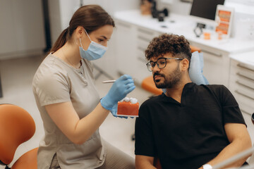 Fototapeta premium Dentist showing teeth model to patient in dental clinic