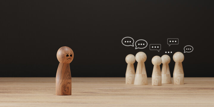 Sad wooden figure excluded from group. Concept of bullying, discrimination, isolation, loneliness, and mental health in society, workplace or school.