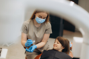 Dentist preparing filling material for little girl in dental clinic