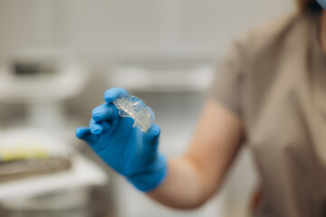 Dentist holding transparent aligner for teeth straightening. Dentist shows aligners, braces, caps