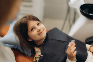 Smiling girl holding invisible orthodontic appliance at dentist office
