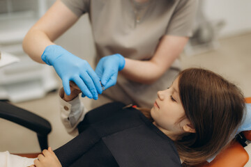 Dentist showing tooth model to young girl in dental clinic