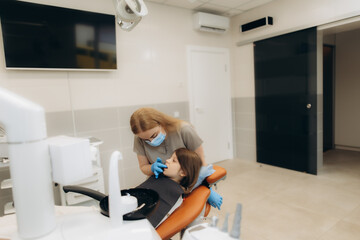 Dentist examining teeth of little girl in dental clinic