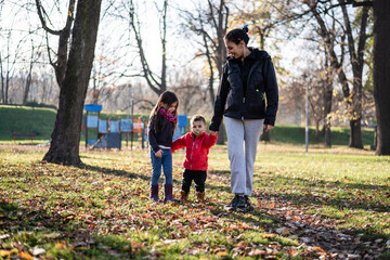 Mother walking with children in autumn park