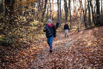 Happy girl running on a path covered with autumn leaves in a forest