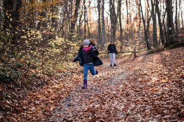 Girl running in autumn forest with mother watching her