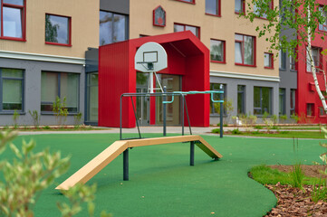 modern school playground with basketball hoop features colorful equipment in front of contemporary...