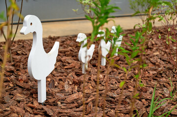 white duck decorations in garden mulch add whimsical charm to natural setting. perfect for yard...