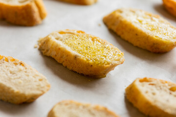  slices of bread neatly arranged in a tray, ready to be baked into crostini