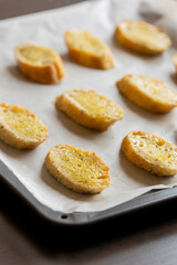  slices of bread neatly arranged in a tray, ready to be baked into crostini