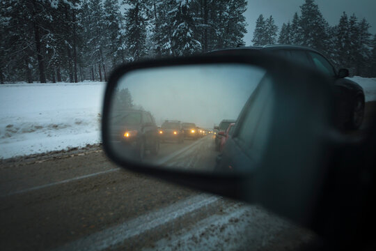 Side mirror view of a line of traffic, traffic jam on Snoqualmie Pass in bad foggy weather.