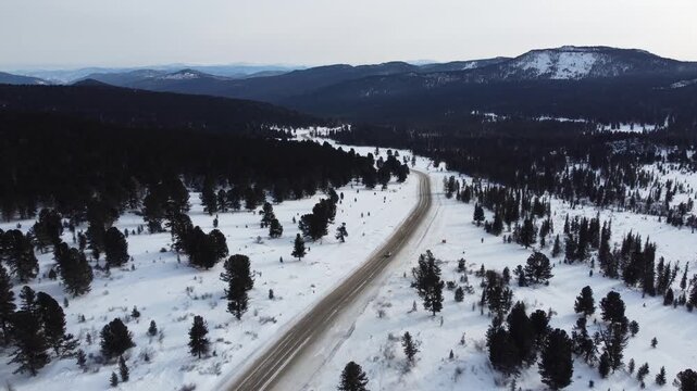 Aerial footage of a winding snow-covered road leading to Ust-Koksa in the Altai Republic, Russia. The video shows scenic winter landscapes with forests, hill