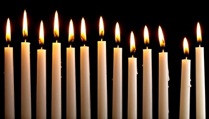 Many lit candles in a row against a black background