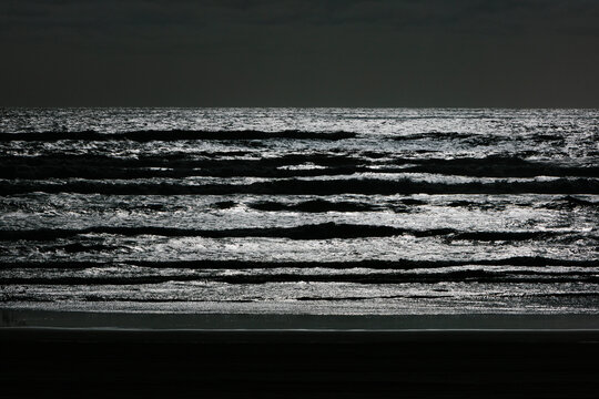Abstract black and white effect, breaking waves and overcast sky at night.