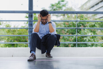 Stressed businessman holding head in hands while sitting on floor