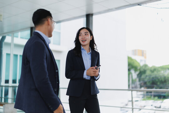 Businesspeople discussing while walking in office corridor