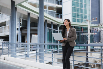 Fototapeta premium Businesswoman working on laptop outside office building