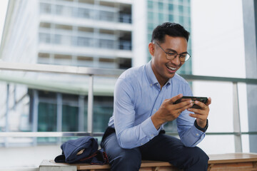Happy entrepreneur is taking break and playing video games on his phone
