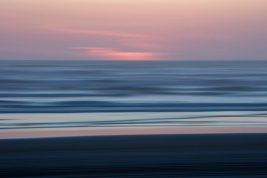 Blurred motion abstract of ocean waves, beach and sky at dusk