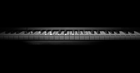A high-contrast, moody shot of a piano keyboard emerging from the darkness, highlighting the keys.