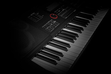 Close-up of an electronic keyboard with dramatic lighting, showcasing black and white keys and...