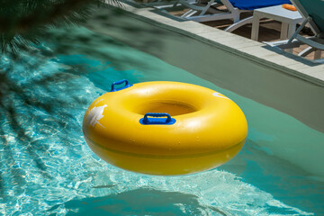 Bright yellow inflatable ring floating in a clear blue lazy river surrounded by lush greenery. A perfect summer scene symbolizing relaxation, fun, and tropical vacation vibes.