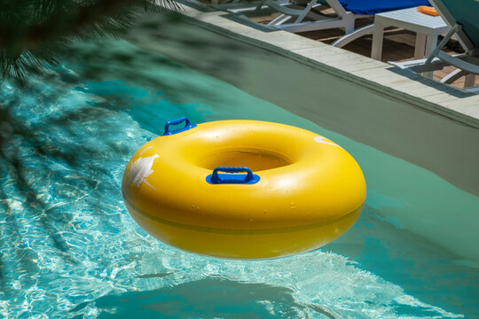 Bright yellow inflatable ring floating in a clear blue lazy river surrounded by lush greenery. A perfect summer scene symbolizing relaxation, fun, and tropical vacation vibes.