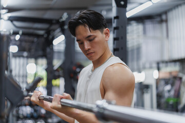 Fototapeta premium Young sportsman lifting weights, concentrating on fitness goals in gym