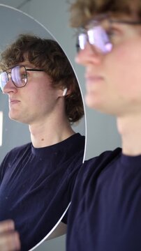 Vertical screen startled and taken aback he touches his chest in disbelief while locking eyes with his reflection trying to process an unexpected rush of feelings and questions