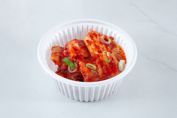A view of a plastic container of kimchi.