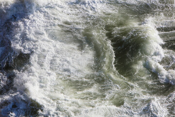 View from above of crashing waves  and churning water.
