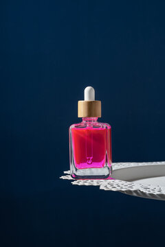 Peonies and pink serum dropper bottle on white doily