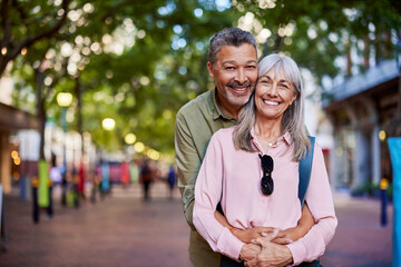 Senior beautiful couple hugging and looking at camera in city street