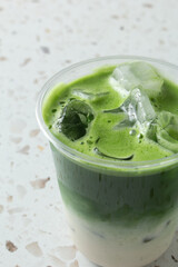 A view of a layered iced cold matcha latte drink.