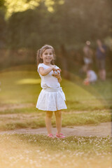 Smiling girl playing in summer park holding a toy