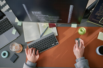Caucasian young adult man working at computer desk using keyboard and mouse, writing code on...